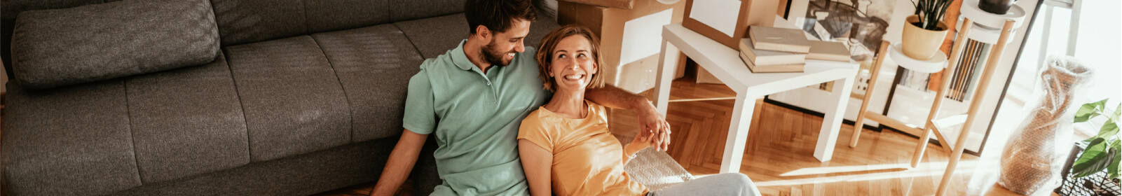 Couple sitting on the floor leaning on the couch.