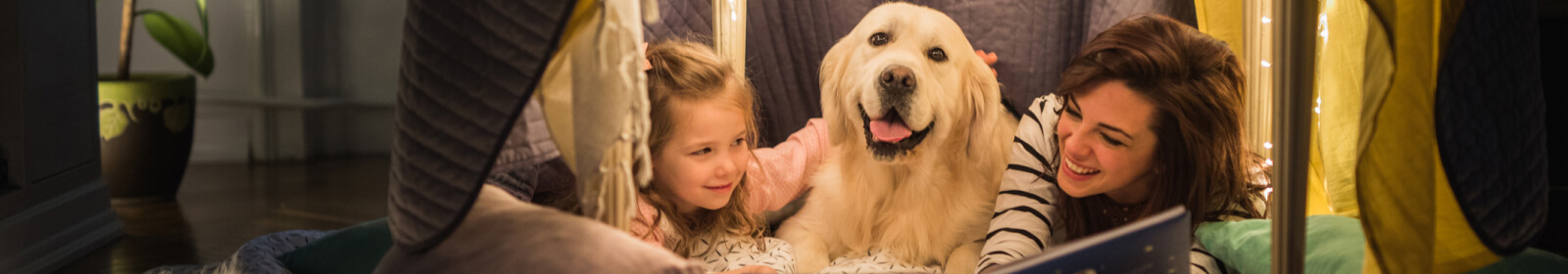 Mother and daughter camping indoors with the family dog.